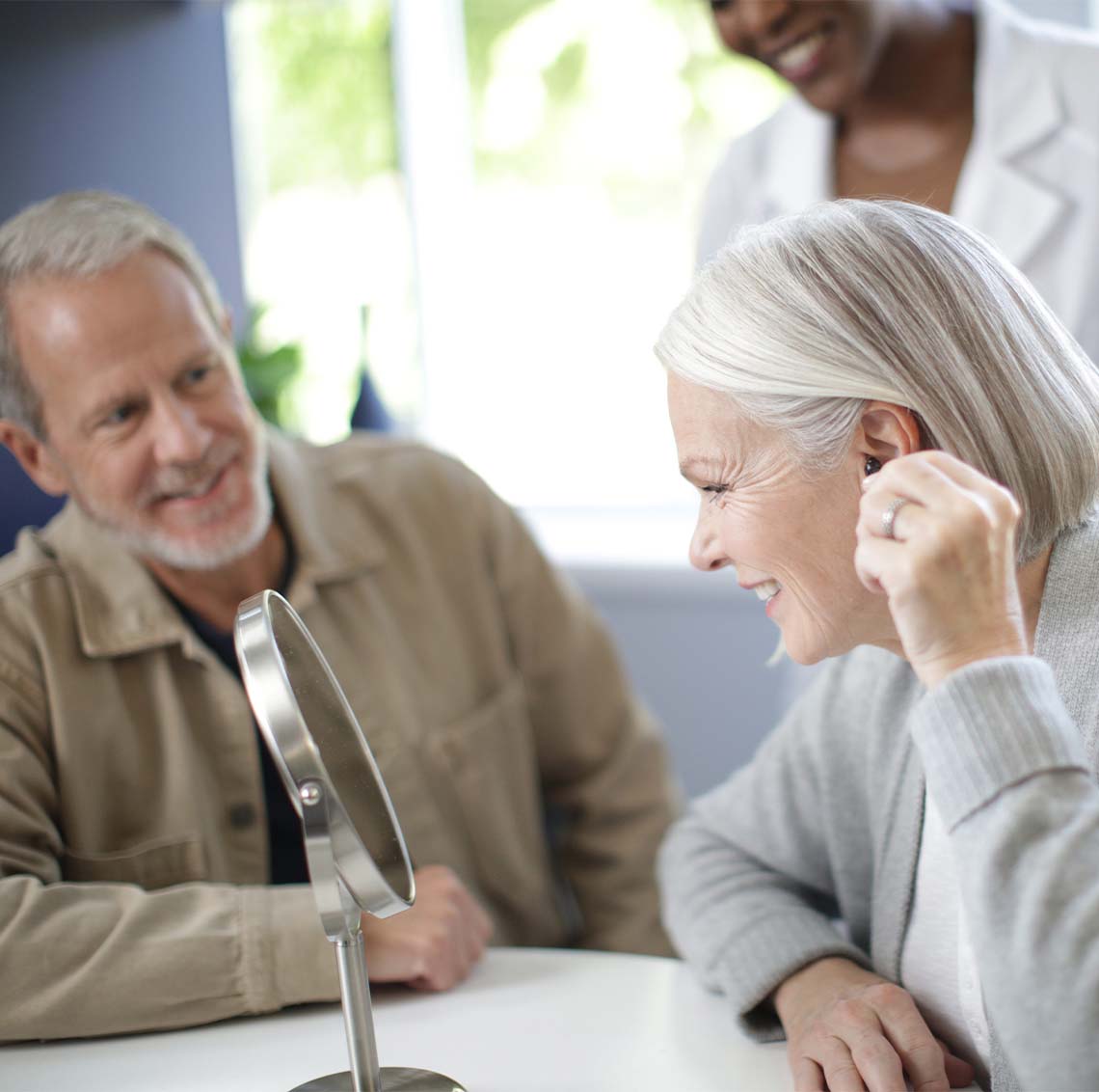 Female patient putting hearing aid in ear