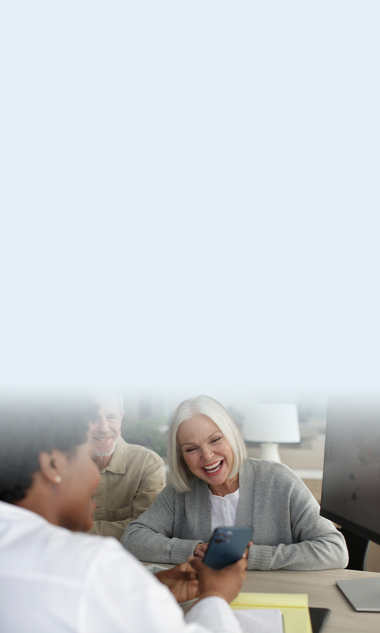 Hearing professional showing female patient mobile device with male in background
