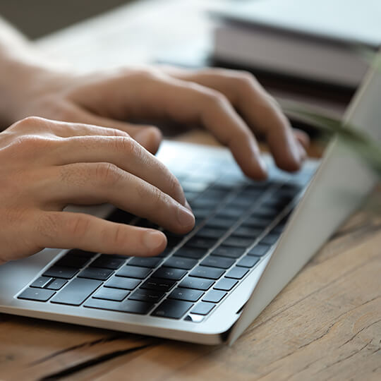 Hands typing on a laptop