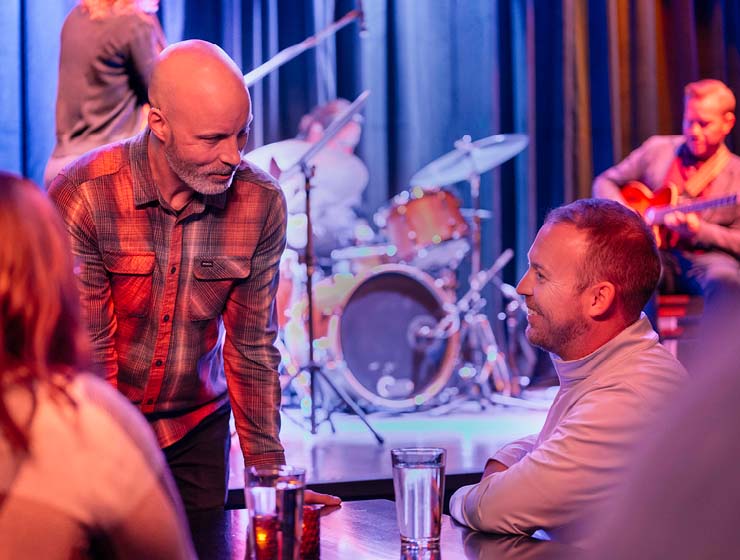 Two men talking with a band in the background.