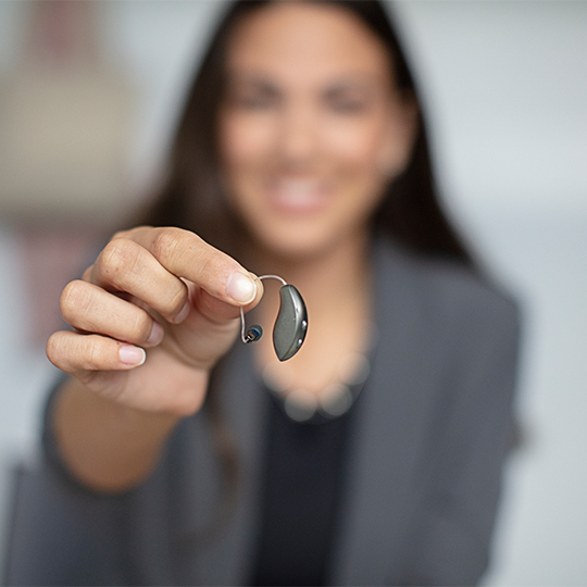 woman holding a small hearing aid